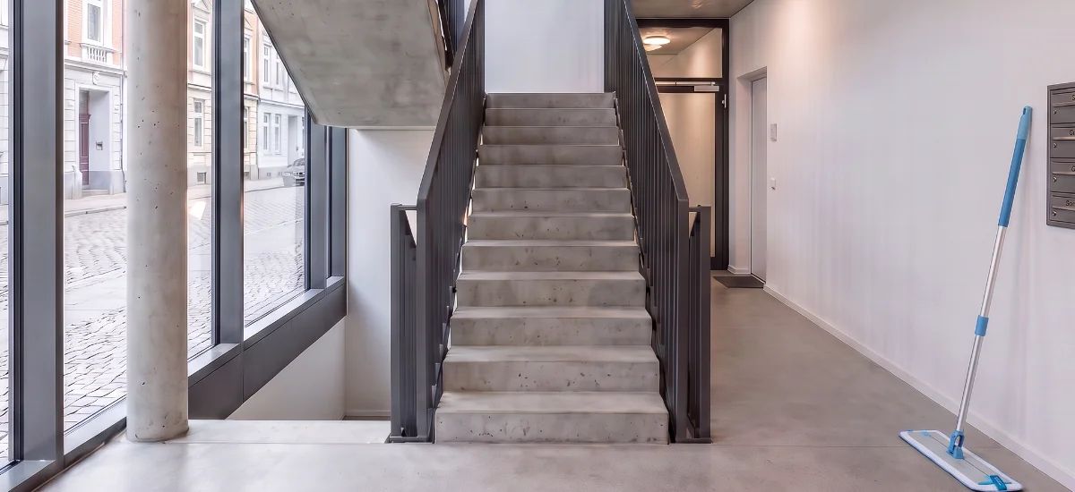 Sauberes, modernes Treppenhaus mit Betonboden und Eisengeländer
